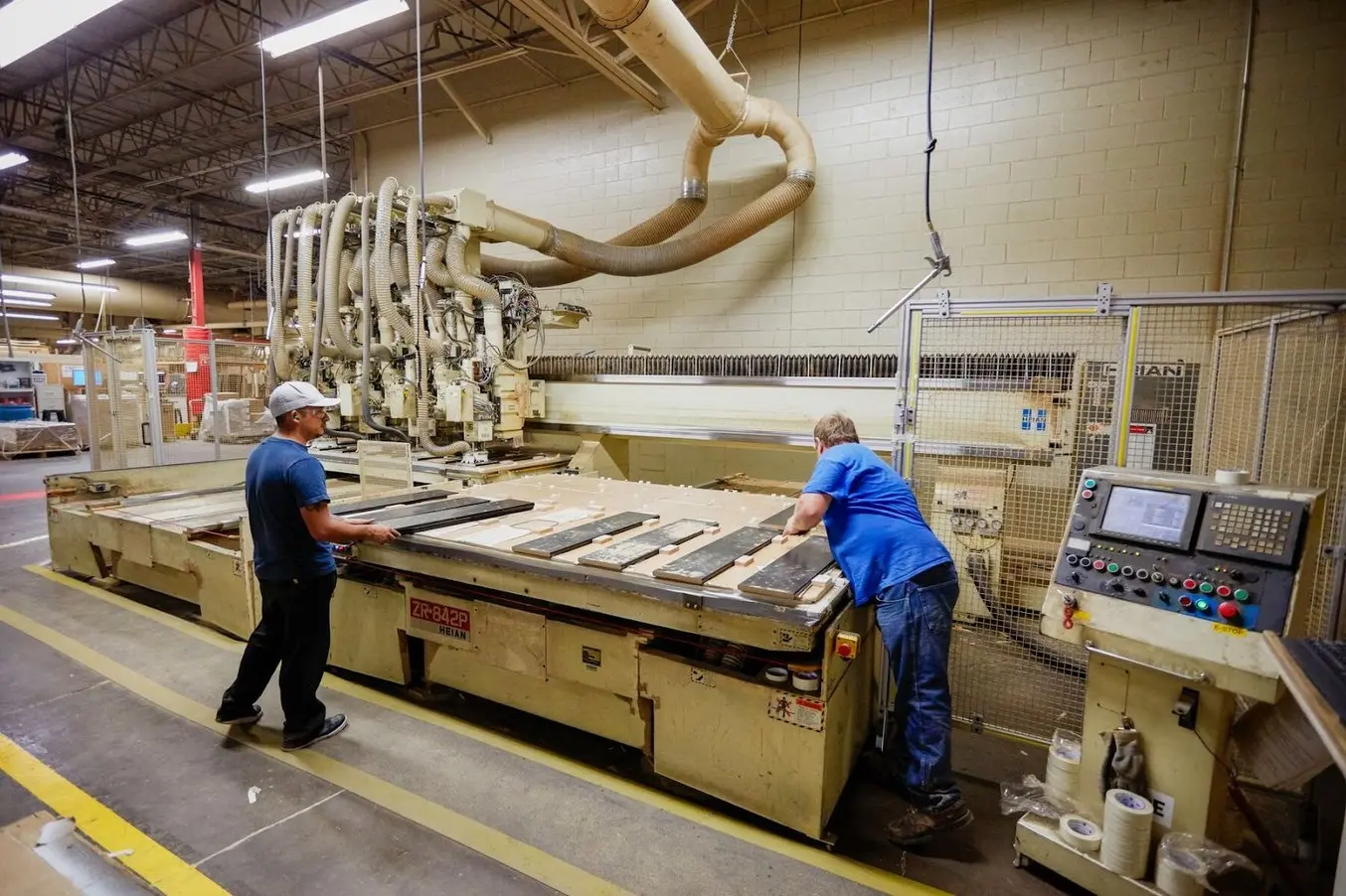 Deux personnes en chemise bleue travaillent à l'usine Ashley Furniture